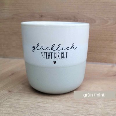 Steinzeugtasse mit dem Text "Glücklich steht dir gut". Tassenfarbe ist grün / mint